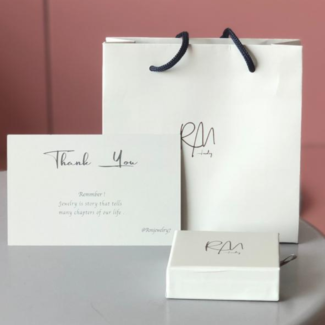 RM Jewelry luxury packaging with thank you card, white box, and shopping bag for a premium gifting experience